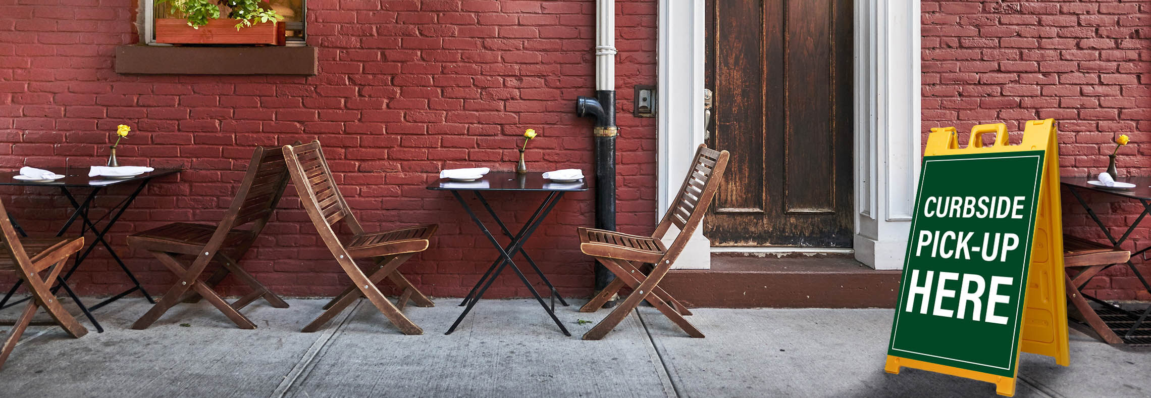 Portable plastic A-frame sign used for curbside pickup instructions outside a cafe.